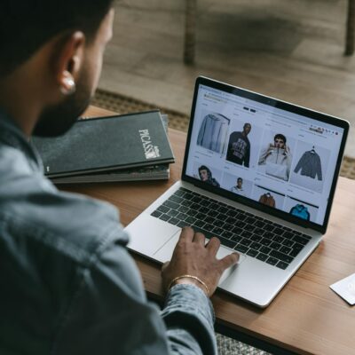Young man browsing online shopping website on laptop indoors.